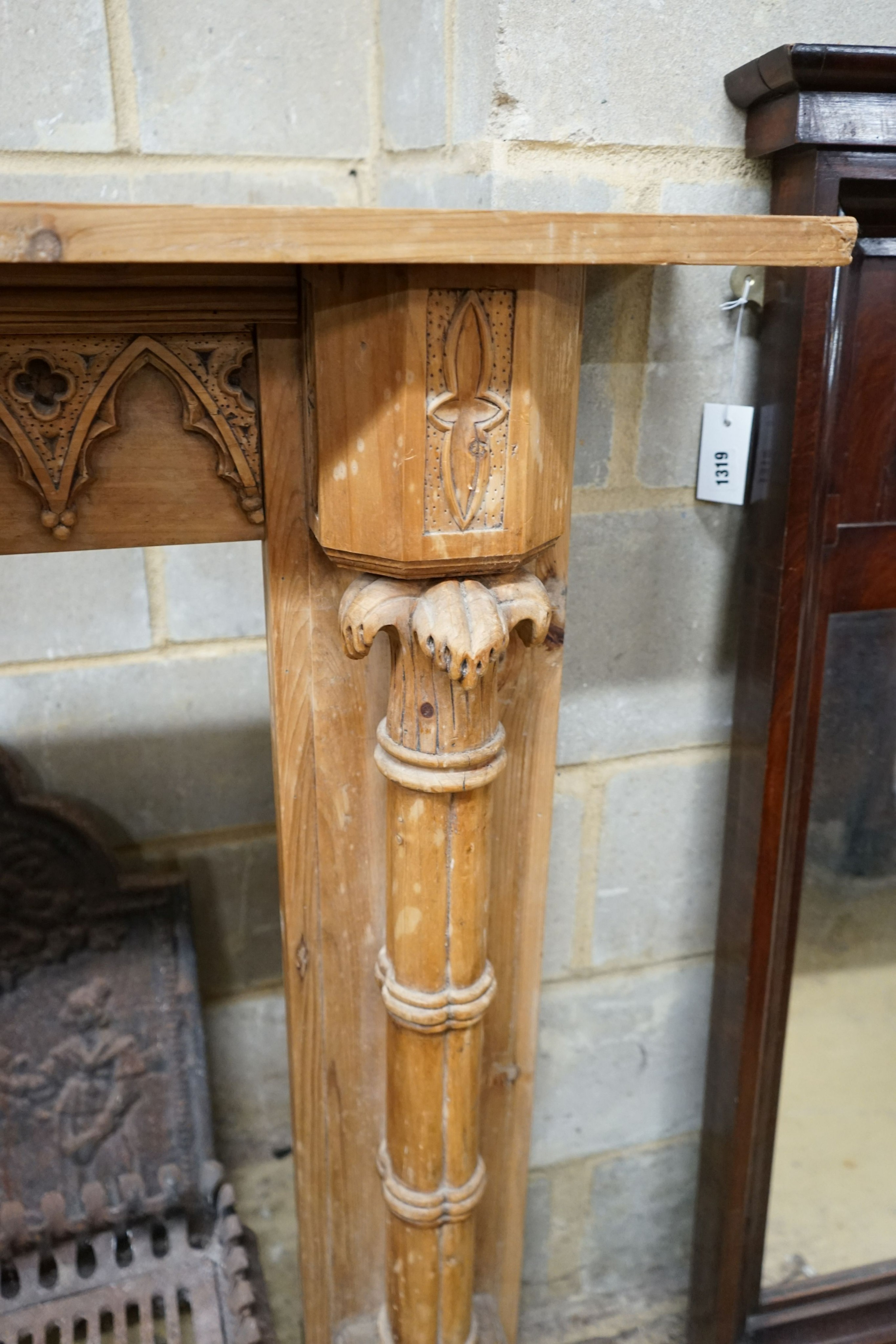 A George III style limewood chimneypiece, in the Strawberry Hill Gothic style, width 150cm, height 111cm together with a cast iron fireback and fire basket (3)